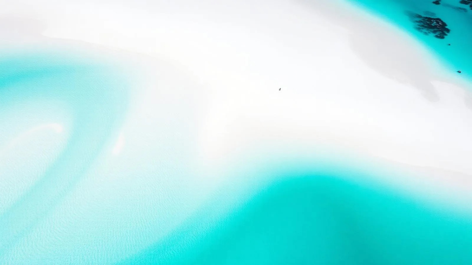 Aerial view of the swirling white silica sand and turquoise tidal channels of Whitehaven Beach in the Whitsundays, Queensland